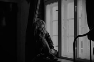 a woman thinking deeply beside her window